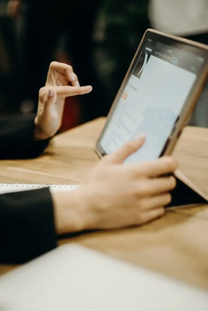 Close-up of hands working on a tablet in a sleek, modern office environment.