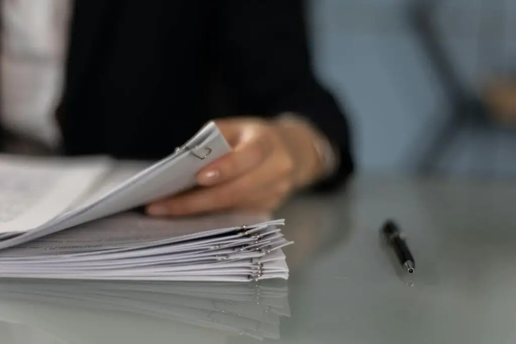 Close-up of a professional organizing a stack of documents on a desk.