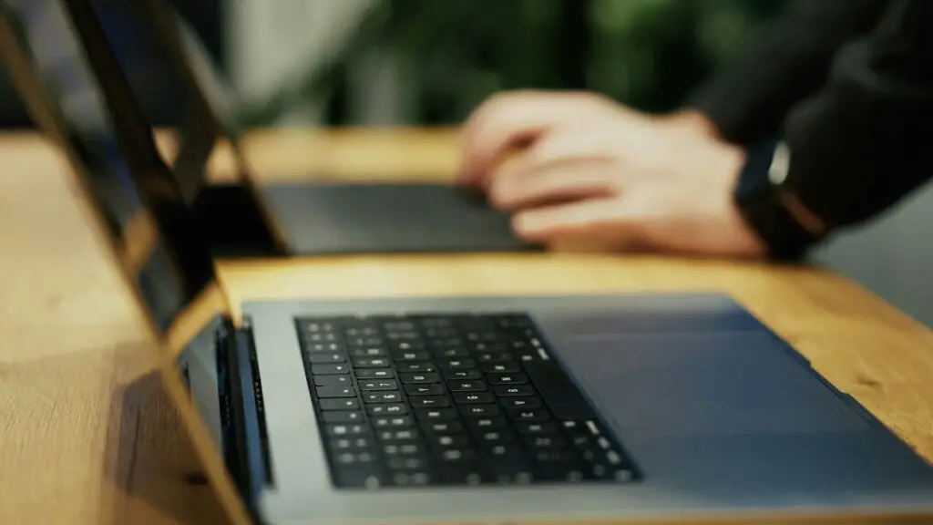 A person typing on a laptop on a wooden table